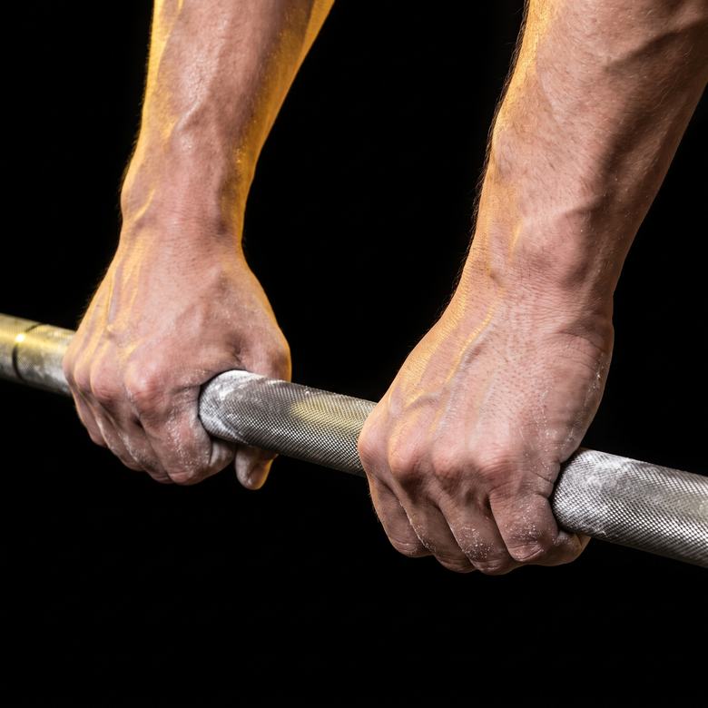 Two chalked hands gripping the knurled centre of a steel barbell.