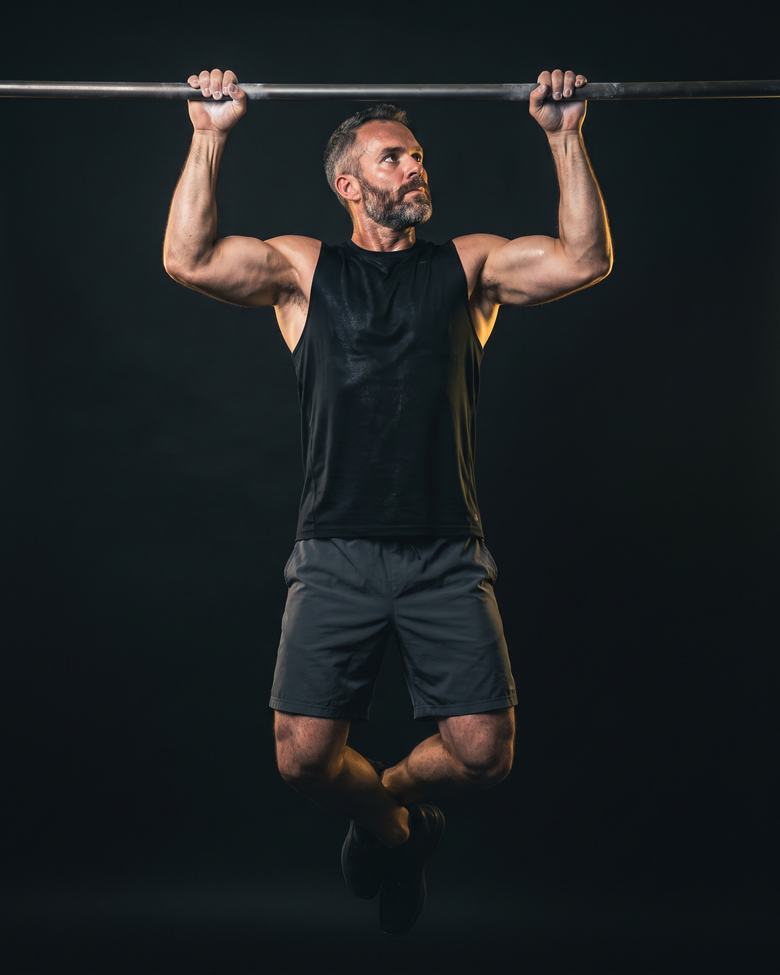 A man pulling himself up to a bar, feet clear of the ground.